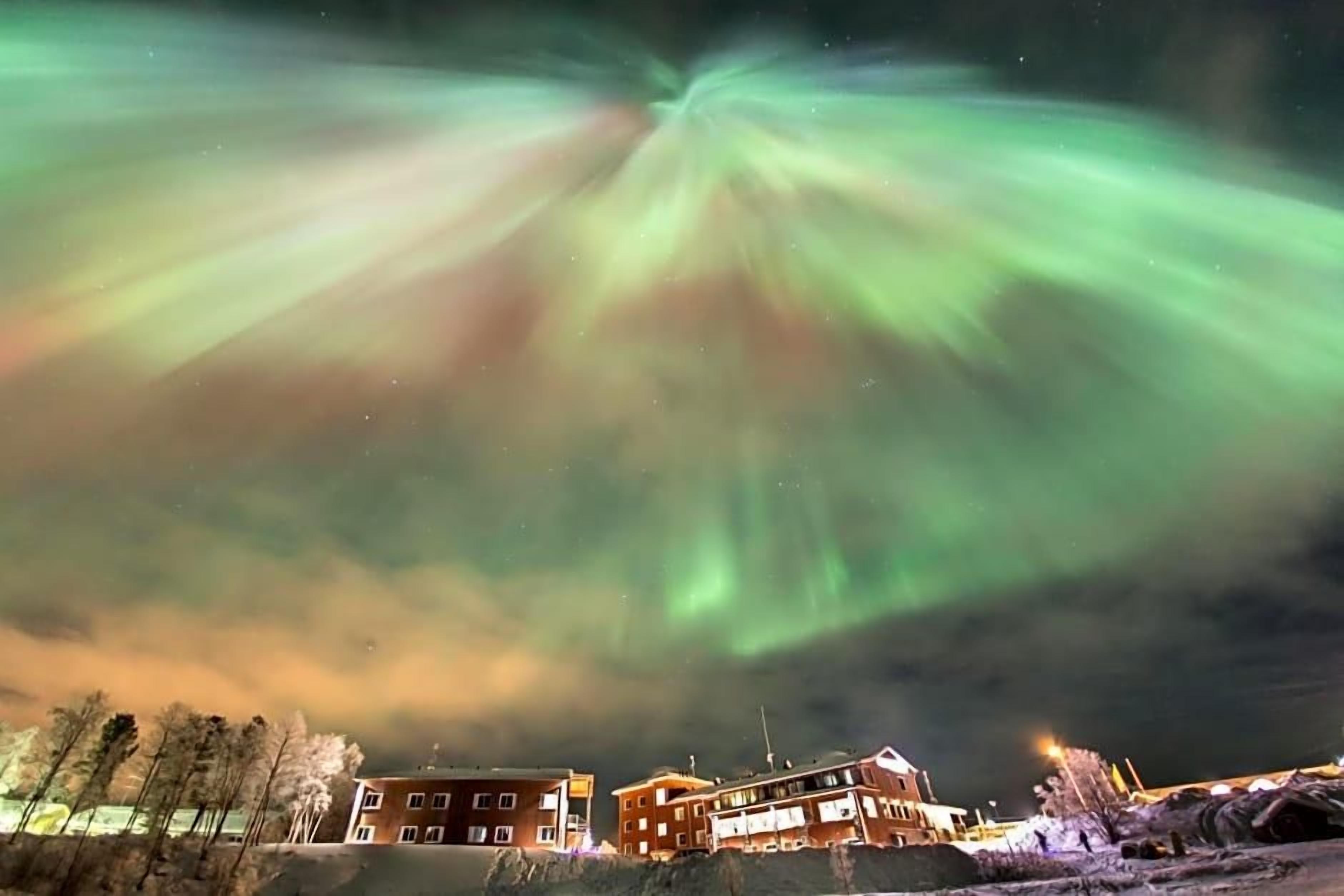 Rakennuksessa on useita ikkunoita ja tasakatto, ja se on ympäröity puilla ja kivillä.