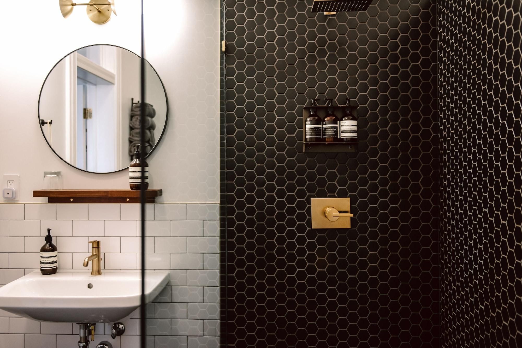 A bathroom with a white sink, a round mirror, and a black hexagonal wall design.
