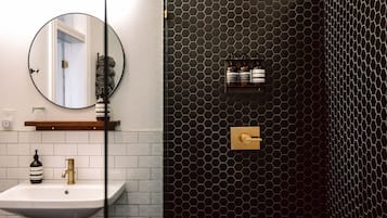 A bathroom with a white sink, a round mirror, and a black hexagonal wall design.