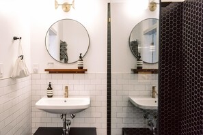 A bathroom with two sinks, a mirror, and a towel rack. - The Wyman Hotel & Inn (Silverton)