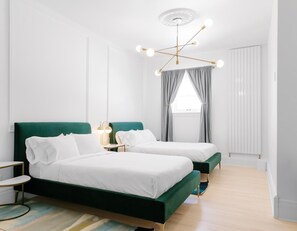 Une chambre moderne avec deux lits, un luminaire au plafond et une fenêtre avec des rideaux.