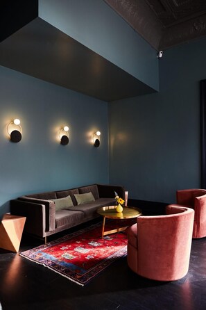 A modern living room with a dark blue wall, a dark sofa, a round coffee table, and a red patterned rug. - The Wyman Hotel & Inn (Silverton)