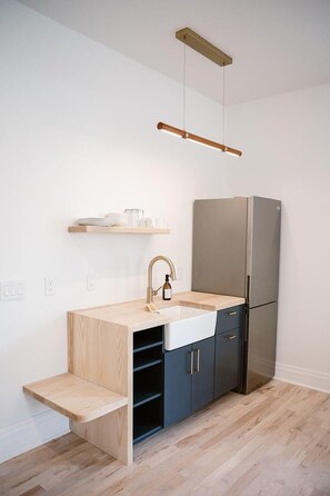 A compact kitchen with a built-in sink, a stainless steel refrigerator, and a wooden countertop. - The Wyman Hotel & Inn (Silverton)