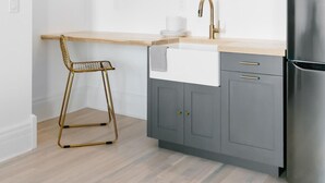 Une cuisine moderne avec un plan de travail en bois, un réfrigérateur en acier inoxydable et une chaise dorée.