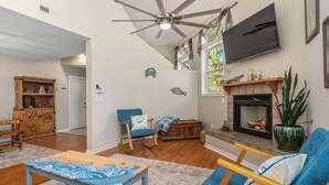 Ein Wohnzimmer mit Kamin, Deckenventilator und Wand-Fernseher.