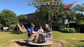 Une aire de jeux avec une balançoire tournante, un toboggan et une structure d’escalade.