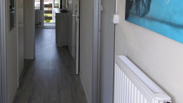 Un couloir avec un radiateur, une porte et une affiche accrochée au mur.
