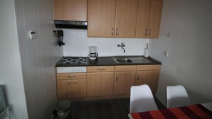 Eine kleine Küche mit Gasherd, Kaffeemaschine, Spüle und Holzschränken.