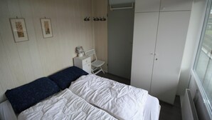 Ein Schlafzimmer mit einem Bett, einem Sessel, einem Kleiderschrank und einer Heizung.