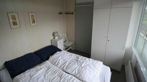 A bedroom with a bed, a chair, a wardrobe, and a radiator.