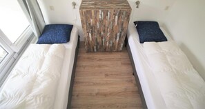 A room with two beds, a central wooden table, and a window.