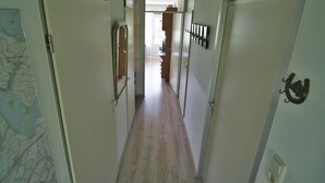 A narrow hallway with wooden flooring, white walls, and doors on both sides. - Comfort Vikingpark 25 (Westkapelle)