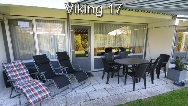A patio area with a table and chairs, a reclining chair with a plaid cushion, and a sliding glass door.