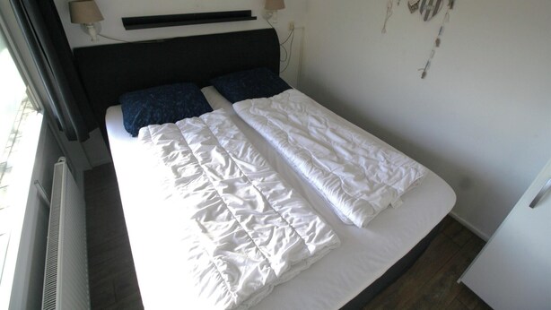 Een bed met witte beddengoed en een donker hoofdeinde.