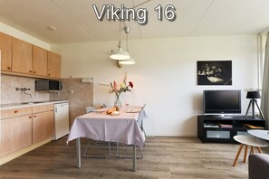 A compact living space with a kitchenette, dining area, and a television. - Comfort Vikingpark 16 (Westkapelle)