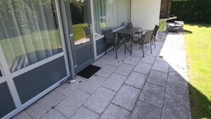 A patio with a table and chairs, a bicycle, and a door with glass panels.