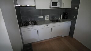 A kitchen with a gas stove, a microwave, a sink, and a coffee maker.