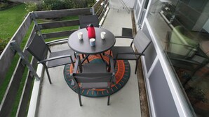 A balcony with a round table and chairs, a red kettle, and a white mug. - Comfort Vikingpark 40 (Westkapelle)