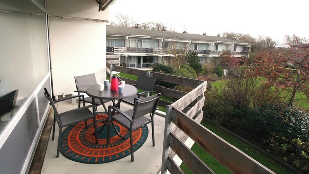 A balcony with a table, chairs, and a red kettle. - Comfort Vikingpark 40 (Westkapelle)