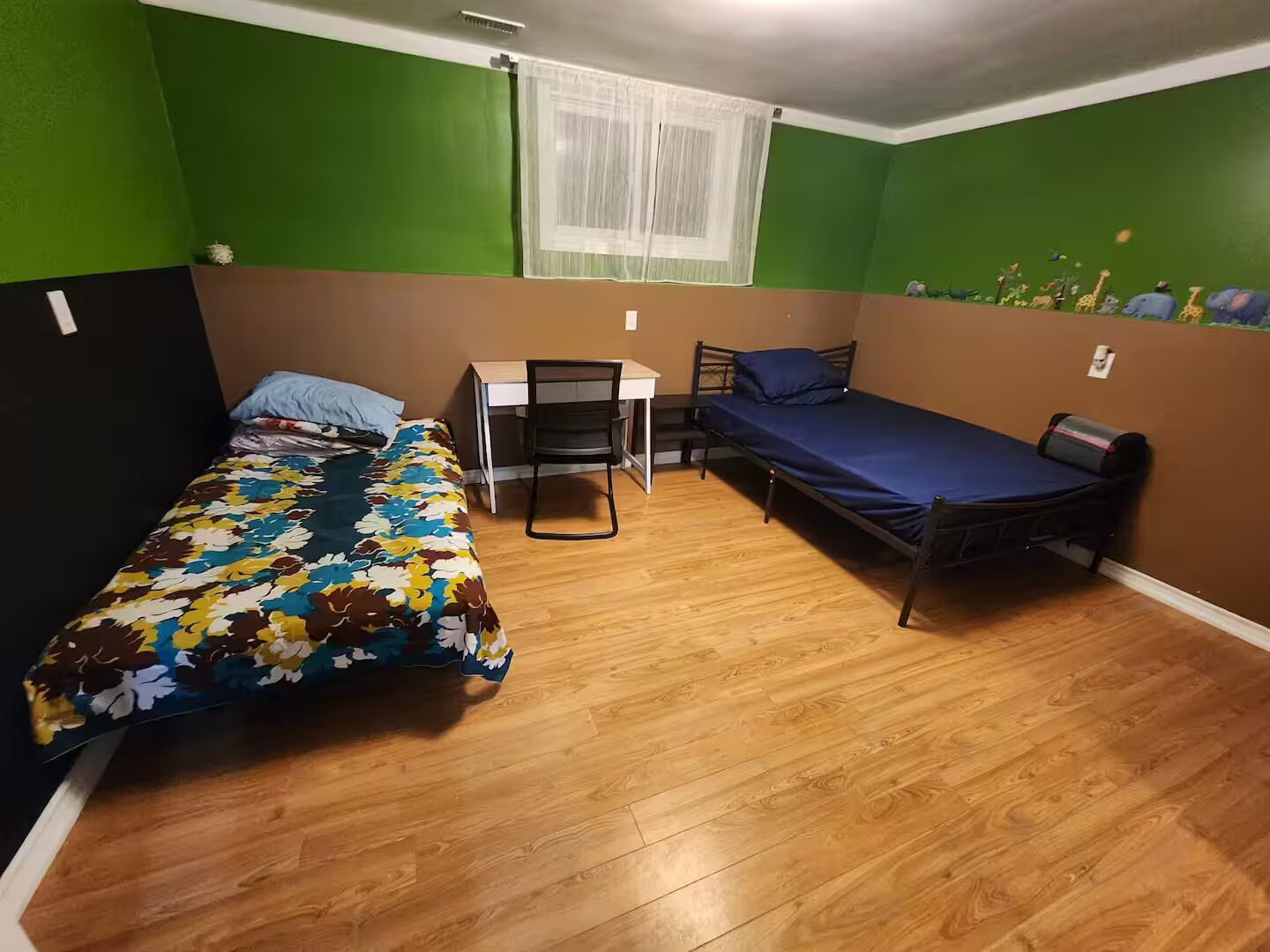 Habitació petita amb dos llits, un escriptori i una cadira.