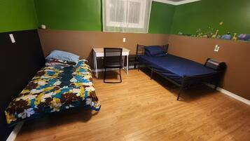 Habitació petita amb dos llits, un escriptori i una cadira.
