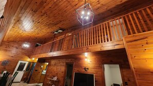 A wooden interior with a balcony, a fireplace, and a television. - Cozy getaway in Brighton (Brighton)