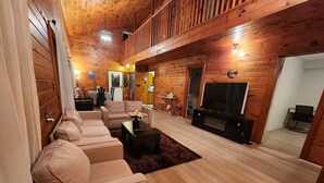 A cozy living room with wooden walls and floors, a sofa set, a coffee table, and a TV. - Cozy getaway in Brighton (Brighton)