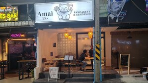 A restaurant named 'Amai' with a cat logo, featuring an outdoor seating area with tables and chairs. - Amai Pancakery and Residence (Pattaya)