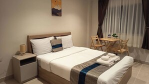 Una camera d'hotel con un letto, un comodino, una lampada e un quadro raffigurante una montagna.