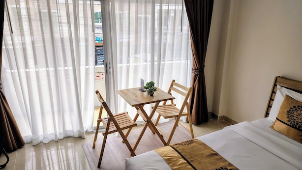 Una camera d'albergo con un letto, un tavolo con sedie e vista dalla finestra con tende.