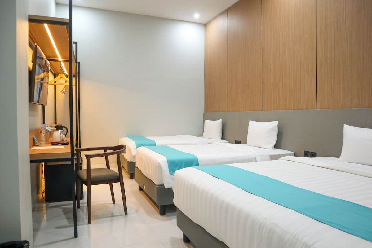A hotel room with two beds, a desk, and a chair.