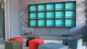 Ein modernes Interieur mit einer großen, an der Wand montierten Anzeige, verschiedenen Polstersitzgelegenheiten und einem minimalistischen Design.