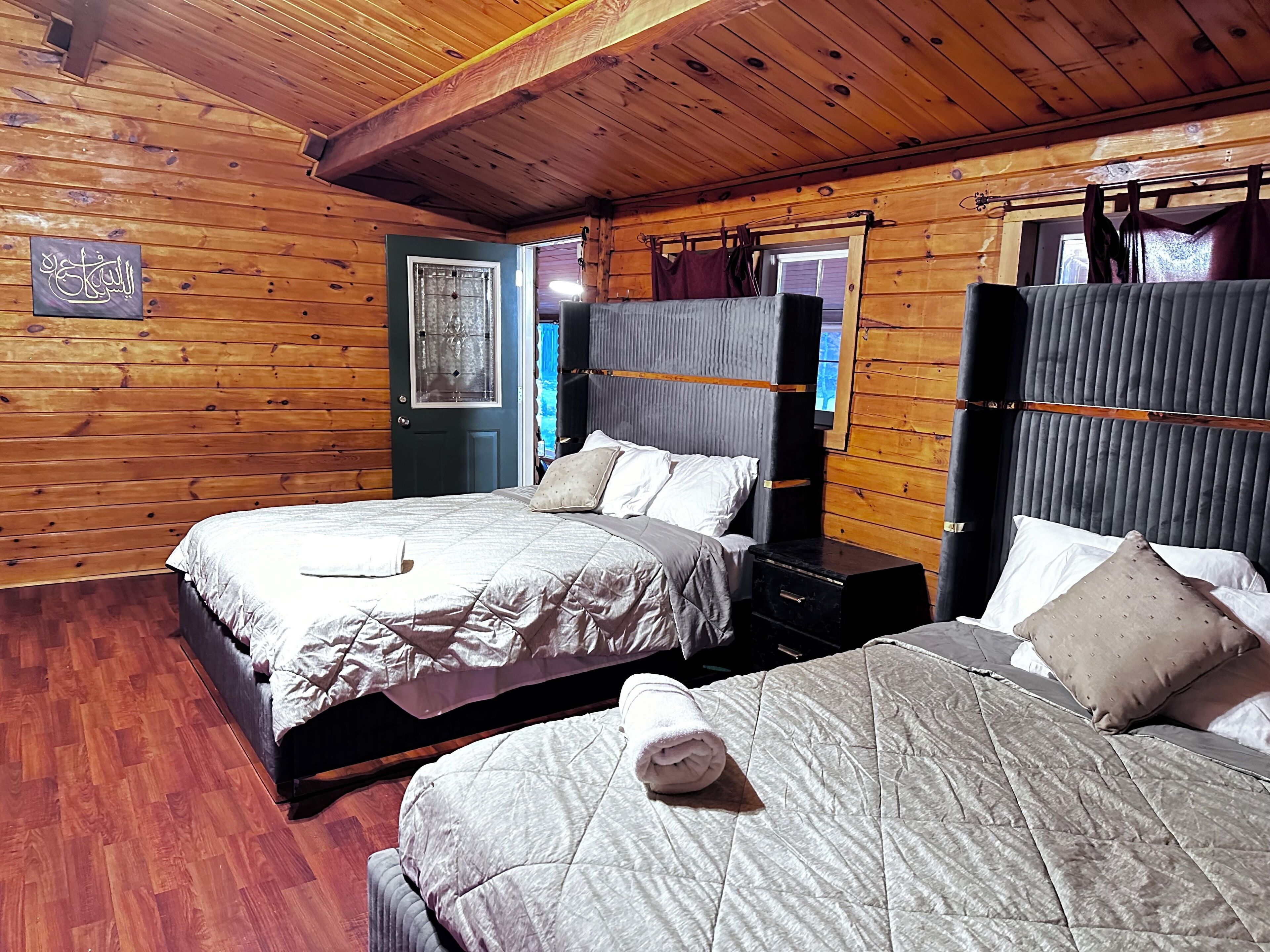 Ein schlicht eingerichtetes Schlafzimmer im Chalet-Stil mit zwei Betten, jeweils mit Kopfteil und Kissen.