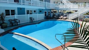 A poolside area with a blue pool, white railings, and a two-story building with balconies. - The Breakaway Beach Condo (North Wildwood)