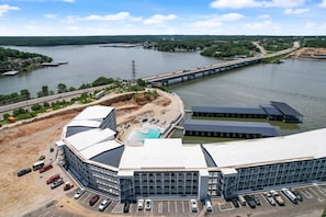 A modern building with a large parking lot, a swimming pool, and a view of a river and bridge.