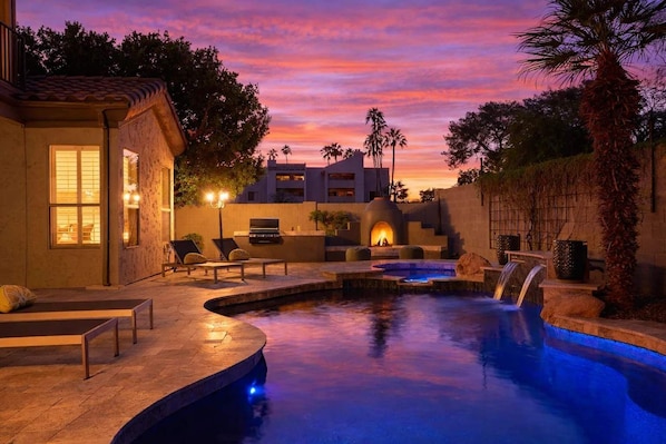 Un área de piscina con sillones reclinables, un jacuzzi y una chimenea.