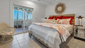 Une chambre à coucher comprenant un lit, une chaise, une table de chevet et donnant sur l’extérieur.