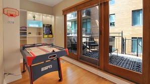 Una stanza con un tavolo da calcio, un cartello che indica la sala giochi e vista sul balcone esterno.