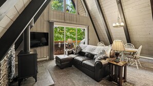 Un dormitorio estilo loft acogedor, con un ventanal grande, chimenea, sofá y comedor.