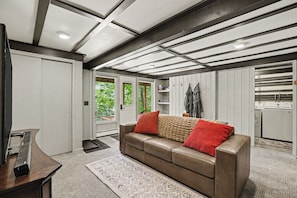 A modern living room with a leather sofa, a wooden coffee table, and a kitchen area visible through an open door. - Harbor Springs, walking distance, base of Nubs two minutes to Highlands+hot tub. (Harbor Springs)