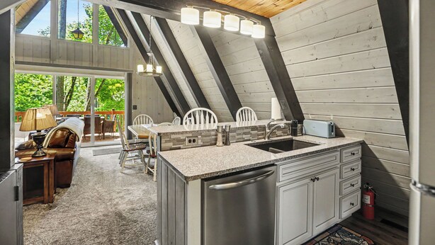 Una cocina equipada con lavavajillas, un comedor con mesa y sillas, y vistas al exterior.