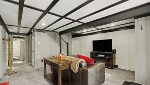 Un sótano con un sofá, un televisor y una mesa de madera.