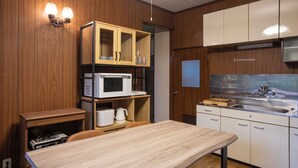 A compact kitchen with wooden cabinets, a microwave, a sink, and a dining table. - rinne 2nd living Nasu Forest (Nasu)