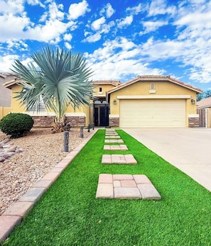 A residential driveway leading to a garage with a well-maintained lawn and a palm tree. - NO FEES! Downtown Resort Pool & Gourmet Kitchen (Gilbert)