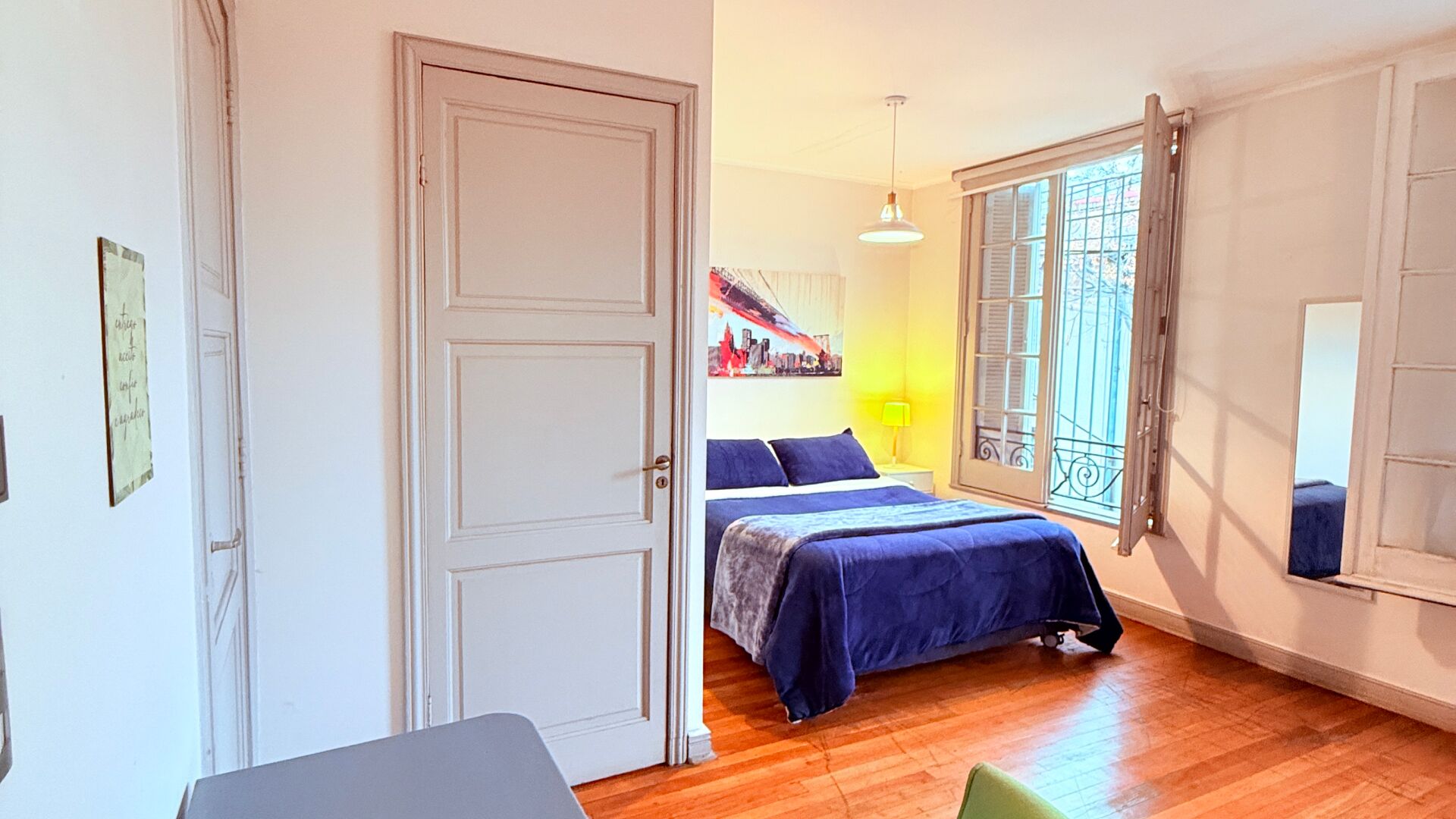 Une chambre à coucher avec un lit, une table de chevet, une fenêtre donnant sur un beau paysage et une porte.