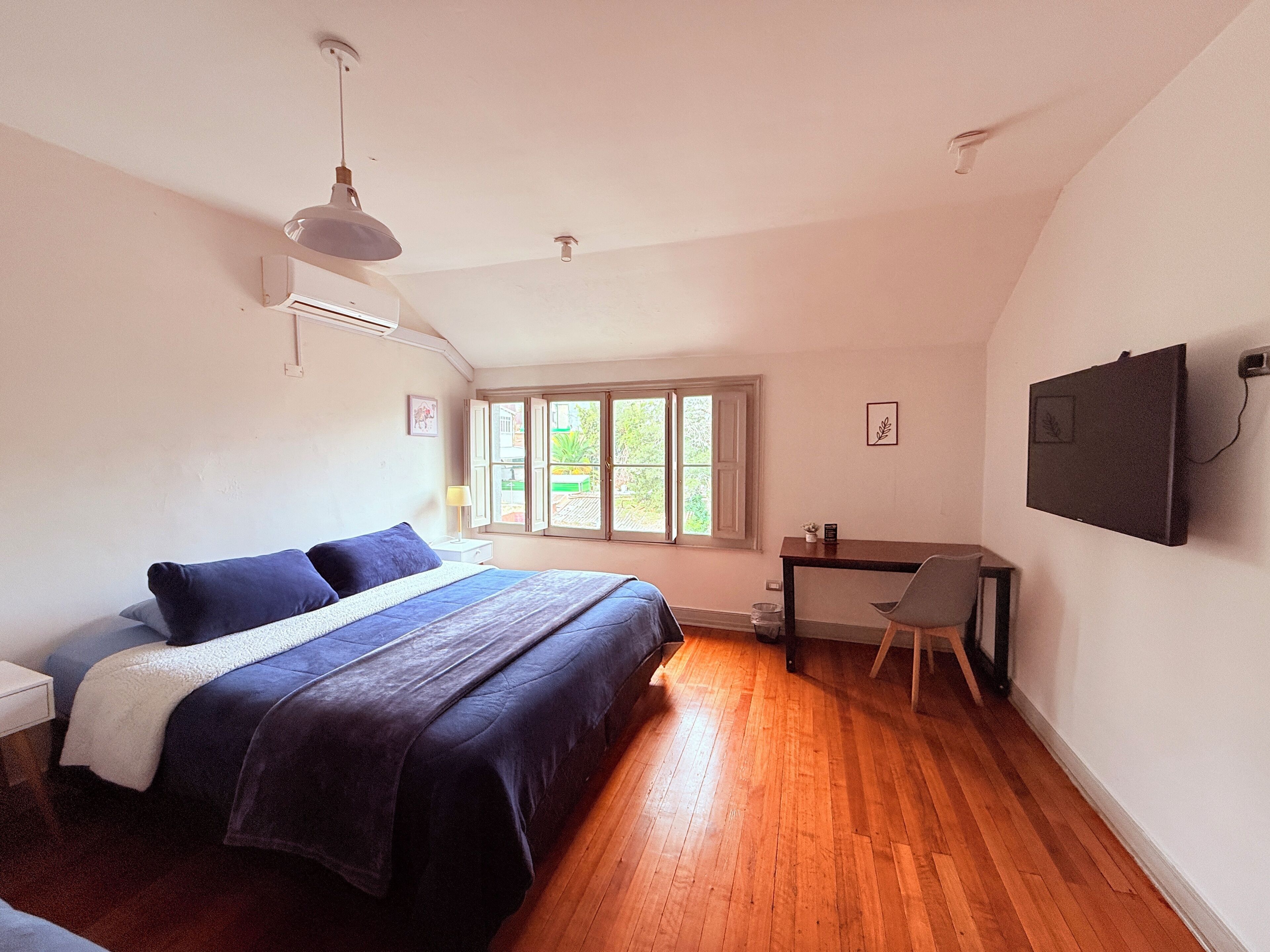 A bedroom with a bed, a desk, and a window.