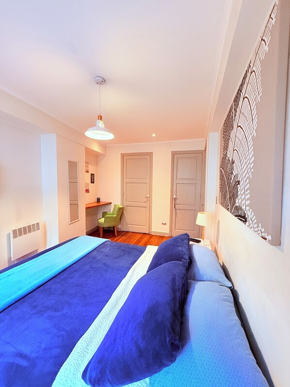 Un dormitorio con cama, una silla, un escritorio y una puerta.