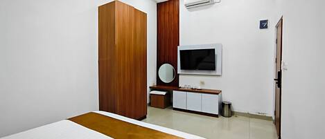 Una habitación de hotel moderna con una cama grande, un armario de madera, un televisor y un baño pequeño.