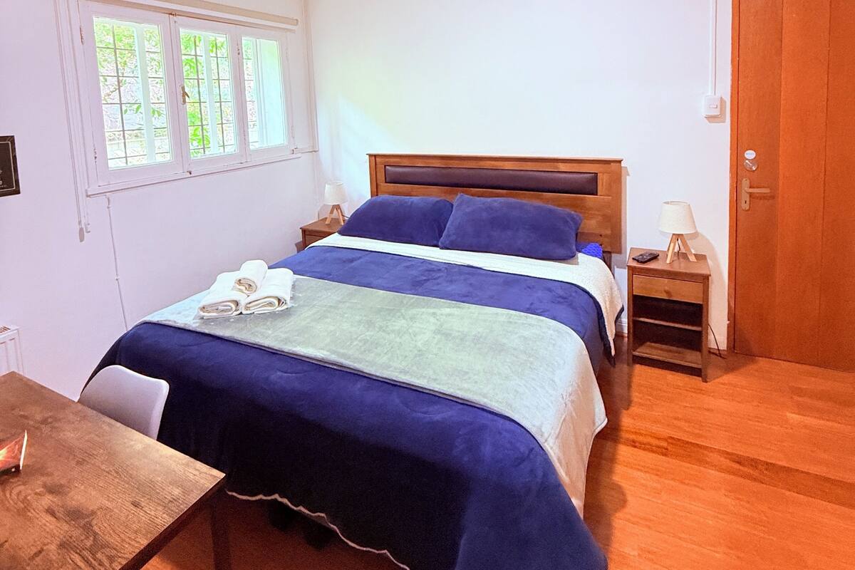 Ein Schlafzimmer mit einem hölzernen Bett, einem Nachttisch, einem Fenster und einer Tür.