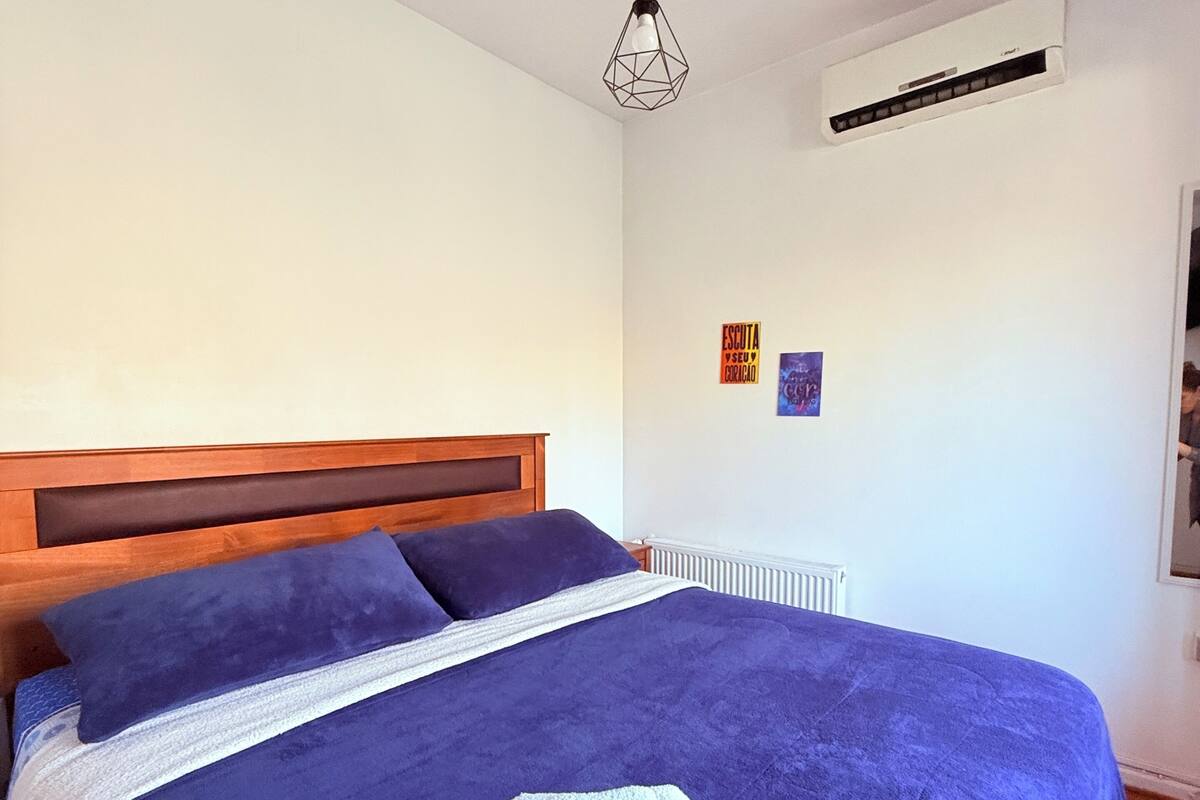 Ein Schlafzimmer mit einem hölzernen Kopfstück, einem großen Bett mit blauer Decke und zusammengerollten Handtüchern auf dem Bett.